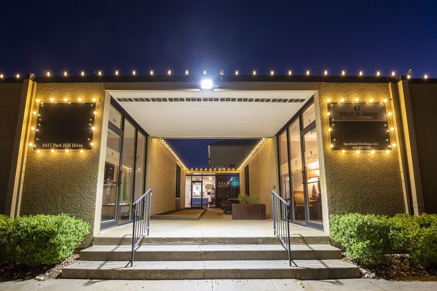 Commercial building entrance lit with warm white holiday bistro lights along canopy and walkway