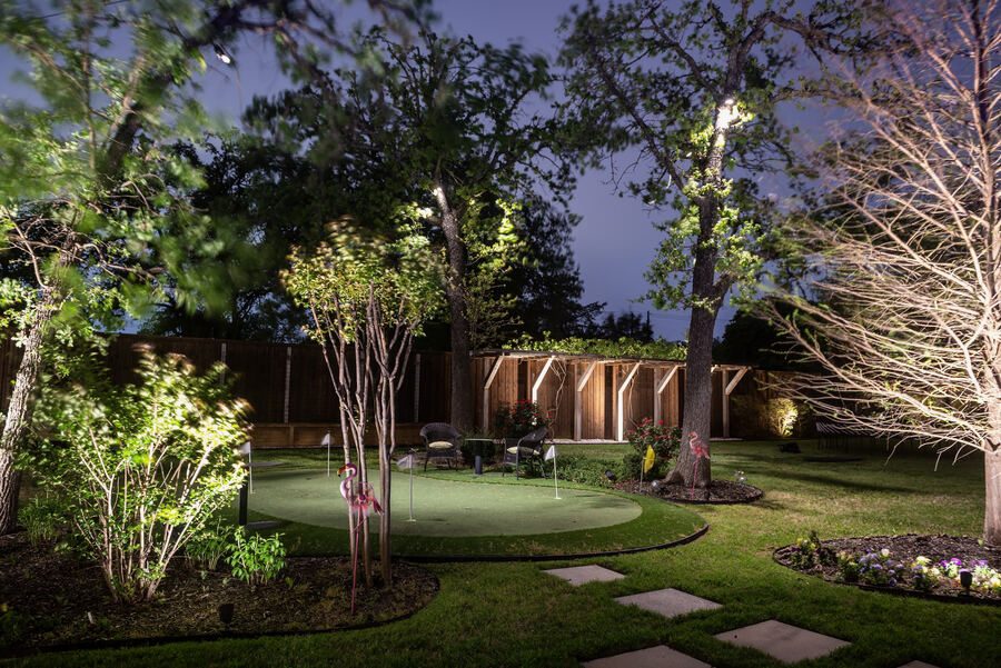 Backyard putting green with tree uplighting and string lights