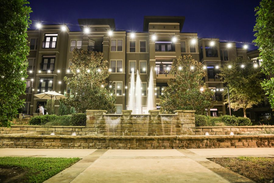 Commercial courtyard with string lights and fountain at night